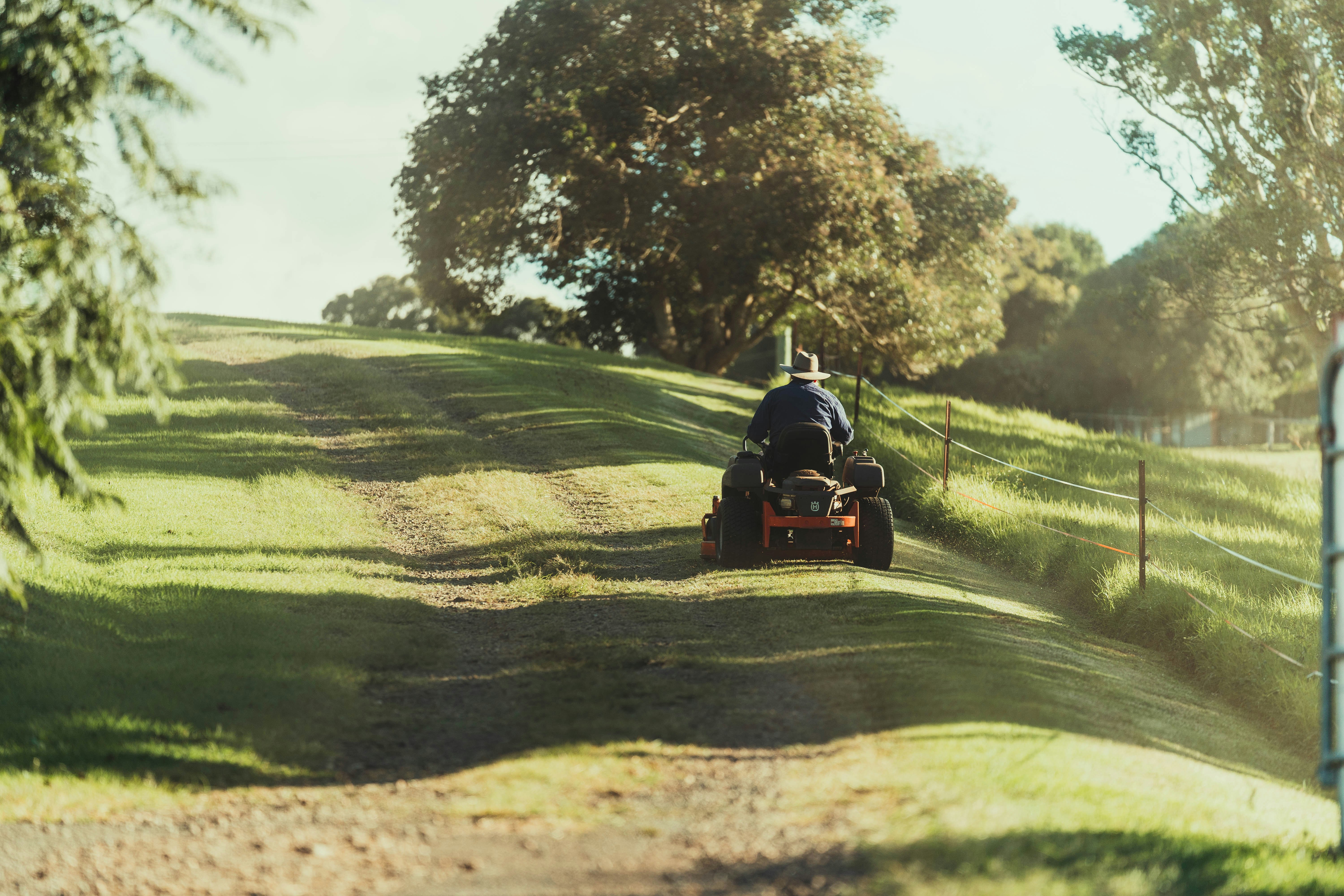 man riding on red atv on green grass field during daytime